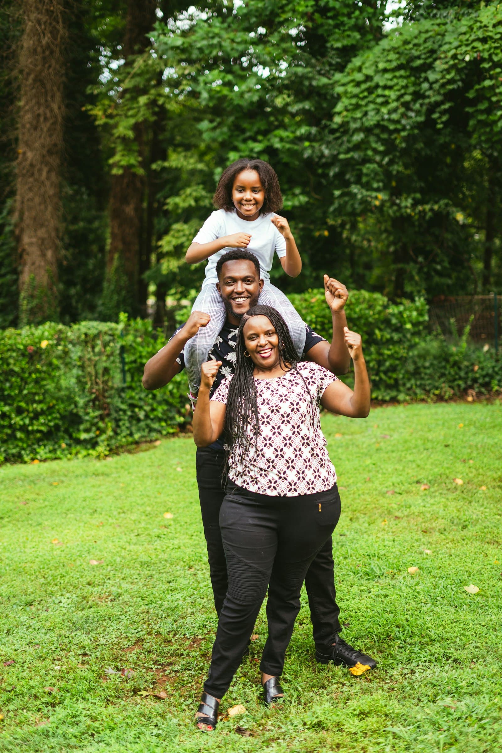 A happy family outdoors, a child riding on her father's shoulders
