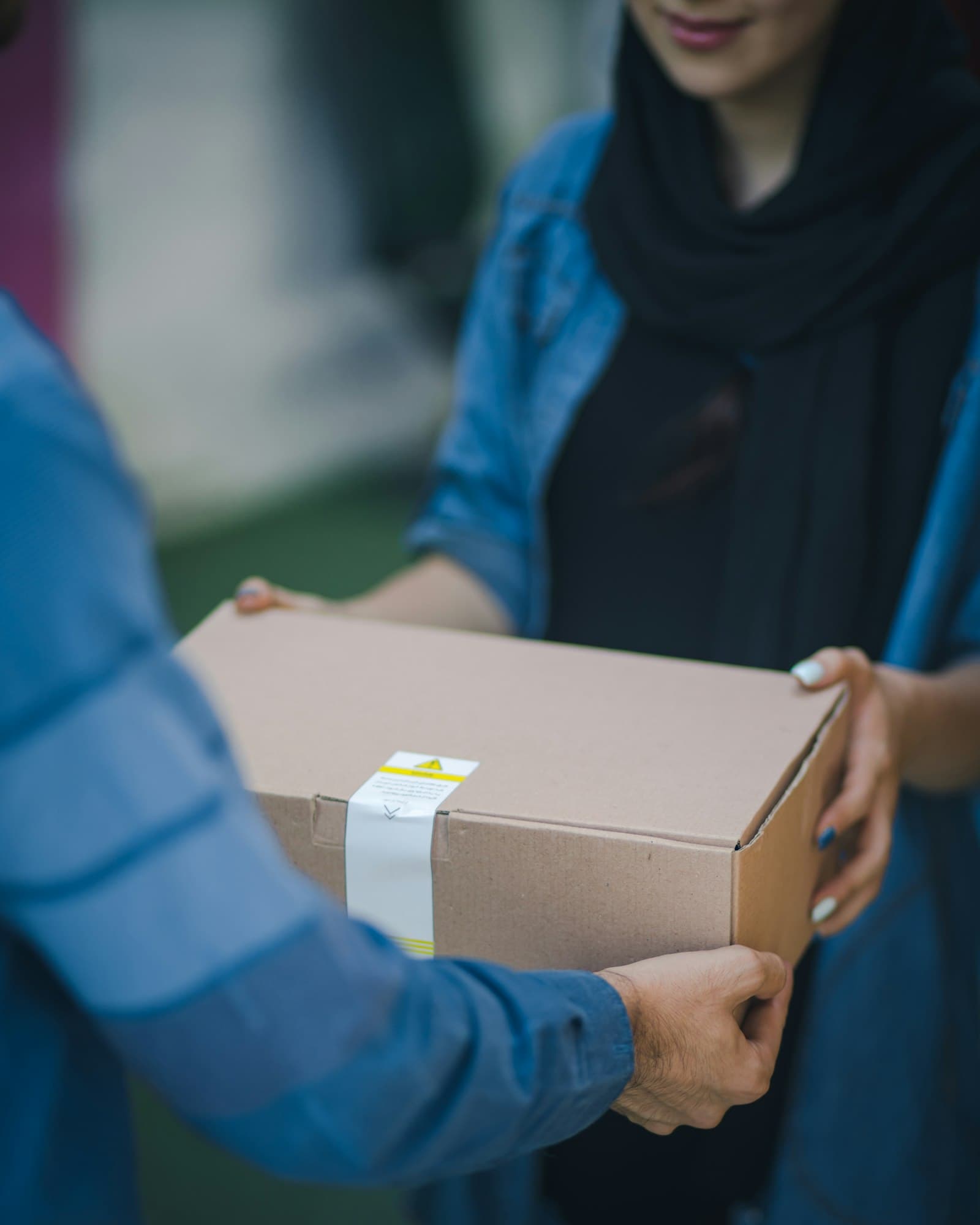 One person handing a cardboard parcel to another