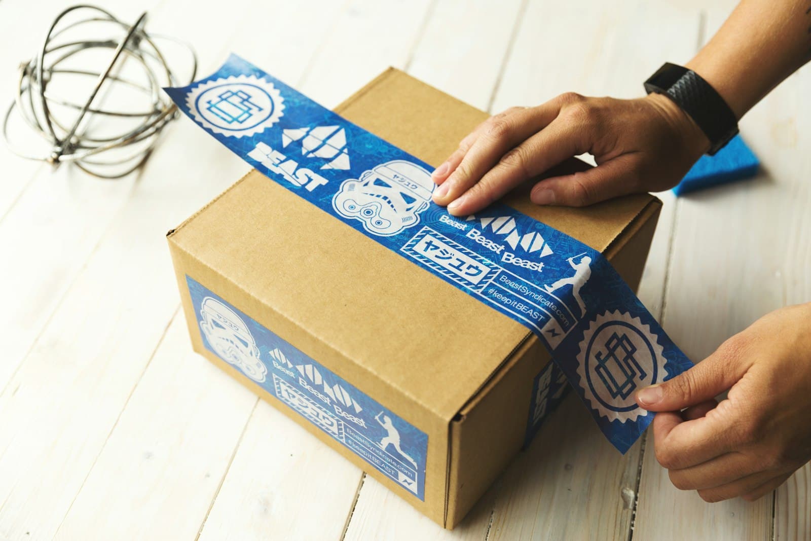 Hands sealing a cardboard parcel with packing tape