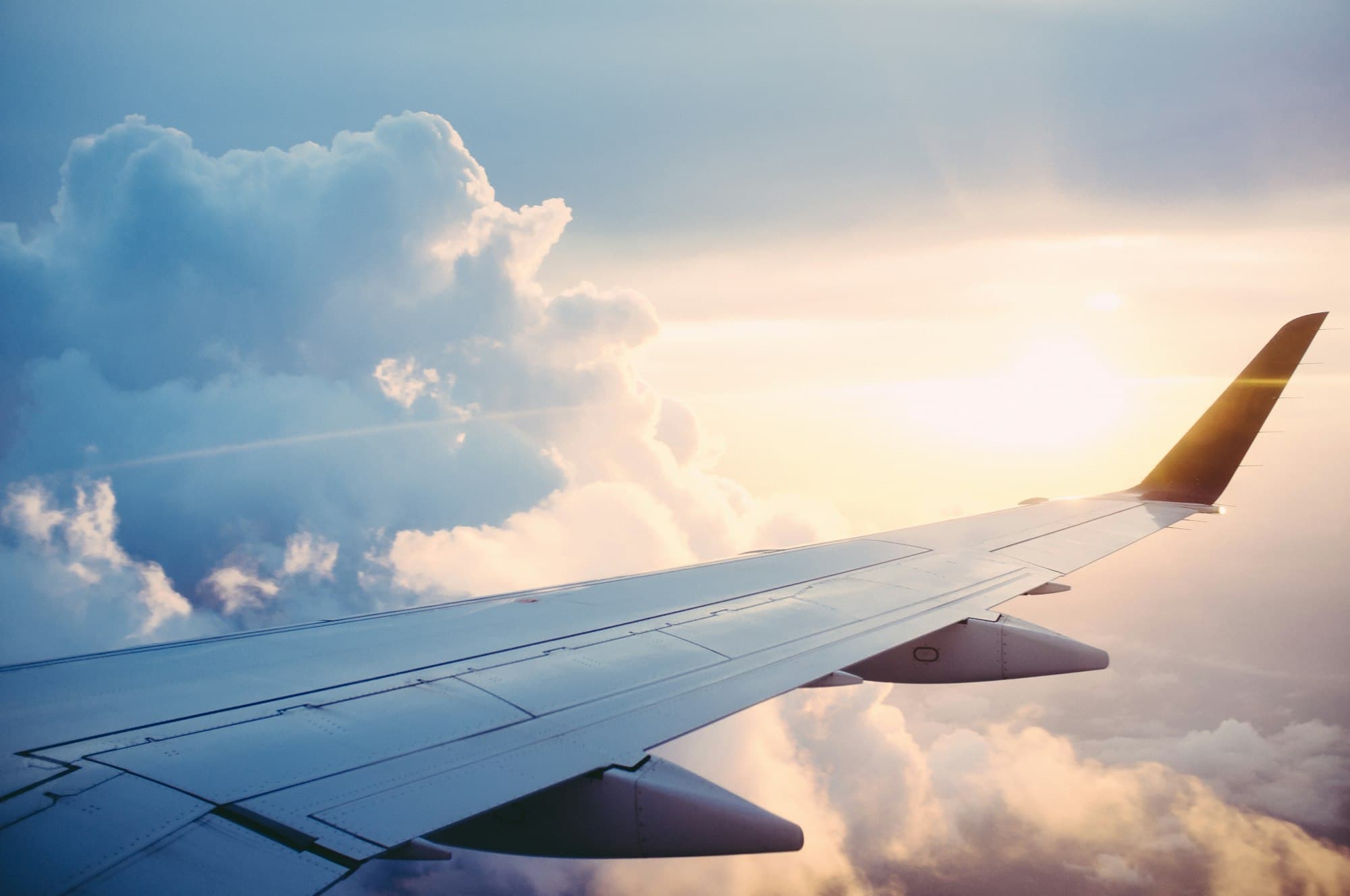 An aircraft wing above the clouds at golden hour